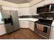 Well-equipped kitchen with stainless steel appliances, white cabinets, granite countertops, and wood-look flooring at 4748 Yellowstone Dr, New Port Richey, FL 34655