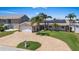 Inviting waterfront home featuring a brick driveway, well-manicured lawn, and tropical palm trees under a clear sky at 5033 Cabrilla Ct, New Port Richey, FL 34652