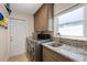 Well-lit laundry room with plenty of cabinet storage space and sink with granite countertops at 5033 Cabrilla Ct, New Port Richey, FL 34652