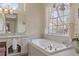 This bathroom features a soaking tub next to a window with a floral display, and a vanity with a plush pink bench at 5110 Championship Cup Ln, Spring Hill, FL 34609