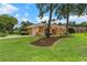 Beautiful exterior showing a manicured lawn, mature trees, and an attached two-car garage at 5110 Championship Cup Ln, Spring Hill, FL 34609