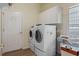 Spacious laundry room featuring a washer and dryer, overhead cabinets, and a door at 5110 Championship Cup Ln, Spring Hill, FL 34609