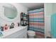 Bright bathroom featuring a white vanity with a round mirror and colorful striped shower curtain at 5640 Ferguson Ct # 2106, New Port Richey, FL 34652