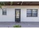 A cozy entrance with a black door and a 'home' welcome mat, flanked by windows on a sunny day at 5640 Ferguson Ct # 2106, New Port Richey, FL 34652