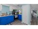 Kitchen featuring blue lower cabinets, stainless steel appliances, and white upper cabinets with a view to a living room at 5640 Ferguson Ct # 2106, New Port Richey, FL 34652