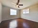 This bedroom features wood flooring, a ceiling fan, and two windows for ample natural light at 5651 Canosa Dr, Holiday, FL 34690