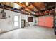 Unfinished garage with exposed rafters, shelves, and a roll-up garage door at 5706 Mockingbird Dr, New Port Richey, FL 34652