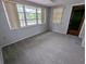 Bright living room with neutral paint, carpet, multiple windows, and a ceiling fan at 5949 1St Ave, New Port Richey, FL 34652