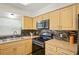 Well-lit kitchen with black appliances, wood cabinetry, and attractive tile backsplash at 6047 Elmhurst Dr # 5A, New Port Richey, FL 34653
