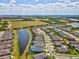 Wide aerial shot showcases a community with houses backing onto a long winding lake and lush green fields in the distance at 6229 Sea Air Dr, Apollo Beach, FL 33572