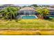 A pristine, screened-in pool overlooks a serene lake, framed by a well-maintained lawn and vibrant tropical foliage at 6229 Sea Air Dr, Apollo Beach, FL 33572