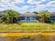 View of a screen-enclosed pool next to a lake with a manicured lawn and lush tropical plants in the background at 6229 Sea Air Dr, Apollo Beach, FL 33572