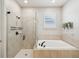 Bathroom featuring a glass shower, soaking tub, tile surround, and a bright window, offering a relaxing space at 6229 Sea Air Dr, Apollo Beach, FL 33572
