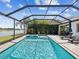 Backyard pool inside screened enclosure with view of the water and palm trees at 6229 Sea Air Dr, Apollo Beach, FL 33572