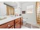 Bright bathroom with cherry wood vanity, neutral tile floors, and decorative accents at 635 Painted Leaf Dr, Brooksville, FL 34604