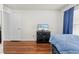 A well-lit bedroom with a blue bed set, wood floors, and a TV atop a dresser at 635 Painted Leaf Dr, Brooksville, FL 34604