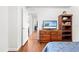 Bright bedroom featuring hardwood floors, a view of the hallway, and a dresser with a television at 635 Painted Leaf Dr, Brooksville, FL 34604