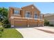 Three-story stucco home featuring multiple car garage, second story balconies and verdant front lawn at 7500 Red Mill Cir, New Port Richey, FL 34653