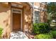 Front entryway view with a dark wood door, manicured landscaping and visible security system at 7500 Red Mill Cir, New Port Richey, FL 34653