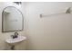 Powder room featuring a pedestal sink, modern faucet and arched mirror with light fixture at 7500 Red Mill Cir, New Port Richey, FL 34653