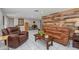 Living room featuring rustic wood accent wall, tile flooring, and comfortable seating at 8505 Lincolnshire Dr, Hudson, FL 34667