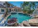 Beautiful pool area featuring a rock waterfall, slide, fire pit, lush landscaping, and multi-story home at 10019 Milano Dr, Trinity, FL 34655