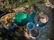 Aerial view of a custom pool area with a waterfall, slide, spa, and fire pit at 10019 Milano Dr, Trinity, FL 34655