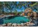 Custom pool with waterfall feature, slide, and adjacent spa showcasing luxurious outdoor living at 10019 Milano Dr, Trinity, FL 34655
