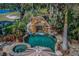 Aerial view of a backyard oasis featuring a lush landscape and custom swimming pool with rock waterfall feature at 10019 Milano Dr, Trinity, FL 34655