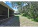 A spacious backyard with a screened-in porch, well-kept lawn, and a view of lush green trees at 10109 Holly Berry Dr, Spring Hill, FL 34613