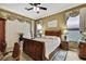 The primary bedroom is complete with a decorative ceiling fan, rich wood furniture and plush bedding at 10109 Holly Berry Dr, Spring Hill, FL 34613