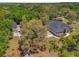 Aerial view of the property showcasing the house, outbuilding, and surrounding mature trees, complemented by ample space at 10645 Fawn Dr, New Port Richey, FL 34654