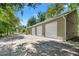 Exterior side-view of a detached three-car garage on a sunny day surrounded by trees at 10645 Fawn Dr, New Port Richey, FL 34654