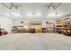 Spacious garage featuring concrete flooring, block walls, overhead lighting and built-in wooden shelving at 10645 Fawn Dr, New Port Richey, FL 34654