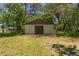 Exterior of an outbuilding with a simple gabled roof, wooden doors, and siding, nestled among mature trees in the yard at 10645 Fawn Dr, New Port Richey, FL 34654