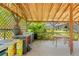 Charming outdoor kitchen and covered patio area featuring a stone countertop, seating area, and view of the backyard at 10645 Fawn Dr, New Port Richey, FL 34654