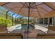 View of the screened-in pool from the table under a large sun umbrella at 10645 Fawn Dr, New Port Richey, FL 34654