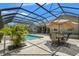 Backyard view of the pool area, patio table with seating, landscaping, and screened-in enclosure at 10645 Fawn Dr, New Port Richey, FL 34654