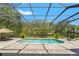 Refreshing screened-in pool area with a paved deck, offering a relaxing outdoor living space with views of the trees at 10645 Fawn Dr, New Port Richey, FL 34654
