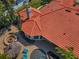 An aerial view of a home with a red tiled roof, manicured landscaping, pool, outdoor kitchen, and fire pit at 10712 Pontofino Cir, Trinity, FL 34655