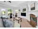 Cozy living room with fireplace, mounted TV, plush sofa, and large windows overlooking the pool and backyard at 10712 Pontofino Cir, Trinity, FL 34655