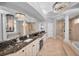 A luxurious main bathroom with dual sinks, marble countertops, a chandelier, and glass shower at 10712 Pontofino Cir, Trinity, FL 34655