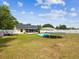 Large backyard with mature trees, white fence, screened patio, trampoline and an inflatable pool at 11630 Pasadena Rd, Dade City, FL 33525