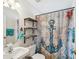 Nautical themed bathroom with decorative shower curtain, and shelving for storage at 11630 Pasadena Rd, Dade City, FL 33525