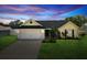Charming home with a well-manicured lawn, two-car garage, and inviting curb appeal at sunset at 11630 Pasadena Rd, Dade City, FL 33525