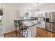 Bright, white kitchen featuring a breakfast bar, stainless steel appliances, and hardwood floors at 11630 Pasadena Rd, Dade City, FL 33525