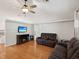 Cozy living room featuring hardwood floors, a ceiling fan, and comfortable leather seating at 11630 Pasadena Rd, Dade City, FL 33525