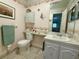 Cozy bathroom featuring floral wallpaper, cabinet, toilet, and neutral tile floors, radiating a welcoming and clean ambiance at 11814 Carissa Ln, New Port Richey, FL 34654