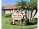 Community sign for Pointe West Condominium Association Inc. amid manicured landscaping and swaying palm trees at 11814 Carissa Ln, New Port Richey, FL 34654