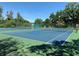 The photo shows a tennis court within the community, surrounded by trees and lush landscaping at 11814 Carissa Ln, New Port Richey, FL 34654